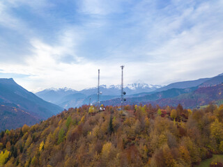 Obraz premium Drone view of two high-voltage towers with antennas in the forest in the mountains on an autumn day.