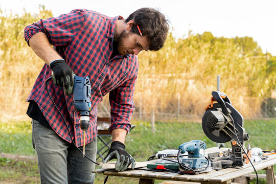 Man drilling wooden designed board 