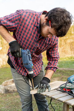Man drilling wooden designed board 