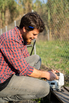 Man sawing wooden board to repurpose it