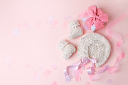 White warm handknitted baby shoes and bonnet for little girl or boy and gift box - concept of first step, birthday party, baby shower, anniversary. Little booties for newborn baby, mother day