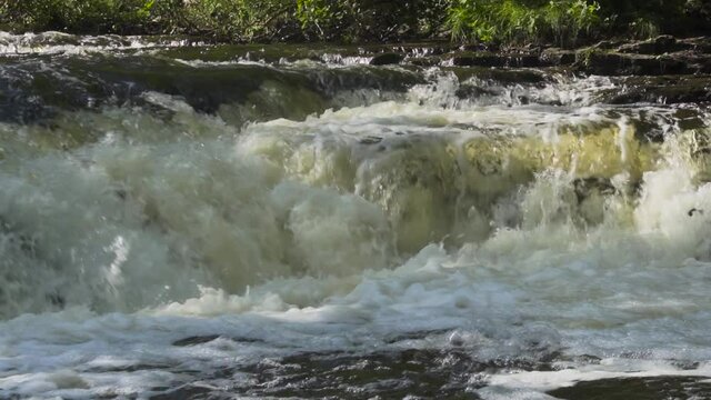 Slow motion river water rushing over the rocks; Ocqueoc Falls, rushing water over rocks in Northwest Michigan after months of rain in late summer--late morning.  20 percent of real time. 436 20