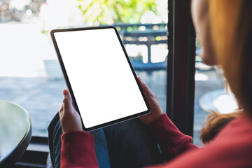 Mockup image of a woman holding digital tablet with blank white desktop screen in cafe
