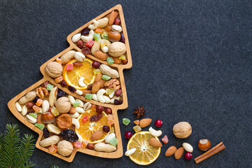Christmas mix of dried fruit and nuts in christmas tree-shaped bowl on dark background
