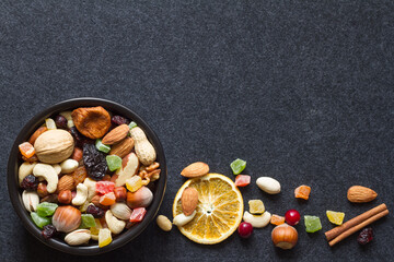 Mix of dried fruit and nuts in bowl on dark background