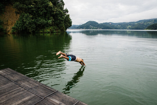 Man Dives Into A Lake On An Overcast Day.