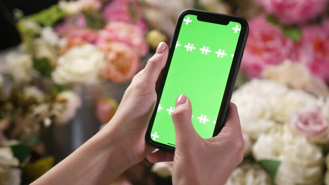 Lady person slides green chroma key screen on iphone smartphone device with fingers. Woman holding phone in hands close up shots, touches, taps, swipes left and right mock up chromakey surface in app.