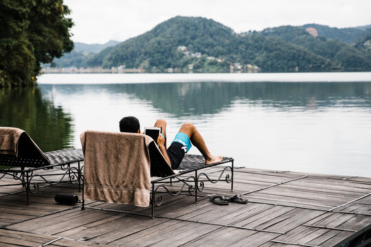 South Asian man using a tablet by the lake.