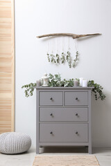 Stylish room decorated with beautiful eucalyptus garland on chest of drawers