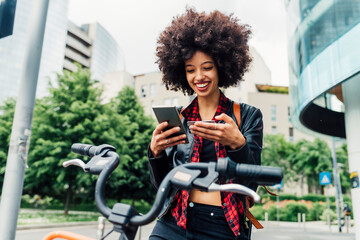 Smiling woman holding credit card while using mobile phone in city
