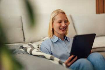 Excited blonde woman, having an online video call on her tablet.