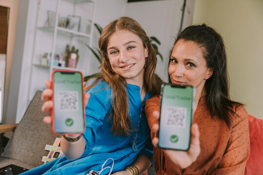 Smiling women showing COVID-19 tracker on smart phone at home