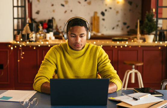 Hispanic student using laptop in kitchen