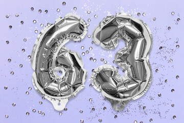 Silver foil balloon number, digit sixty three on a lilac background with sequins. Birthday greeting card with inscription 63. Top view. Numerical digit. Celebration event, template.