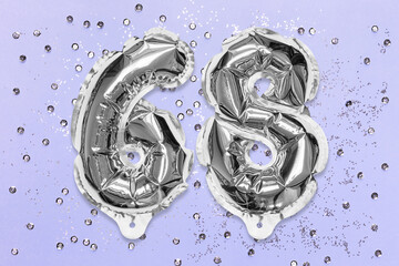 Silver foil balloon number, digit sixty eight on a lilac background with sequins. Birthday greeting card with inscription 68. Top view. Numerical digit. Celebration event, template.