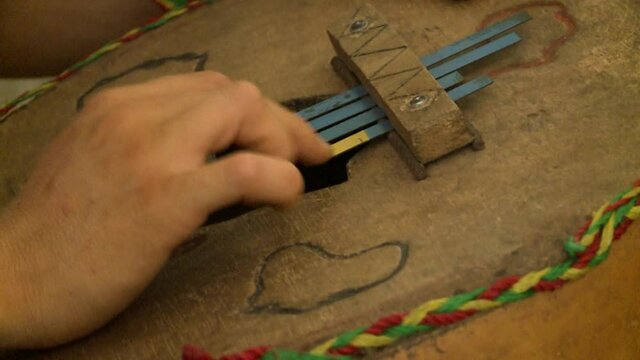 Close-up of hands playing handmade ethnic musical instrument.