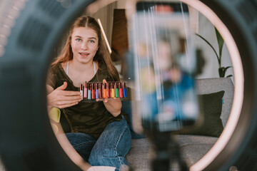 Teenage female influencer showing variety of eyeliners while vlogging at home
