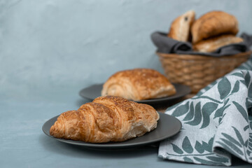 Freshly baked homemade croissants for breakfast. Traditional and whole-grain croissant in a gray plate on a concrete or stone background.