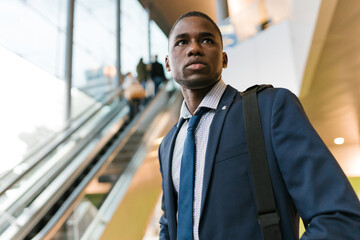 Tired black businessman after flight near escalator