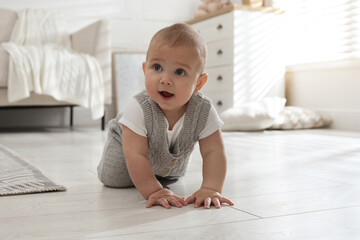 Cute baby crawling on floor at home