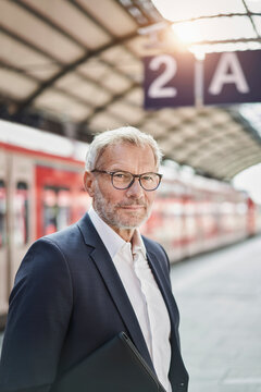 Businessman wearing eyeglasses standing on railroad station platform