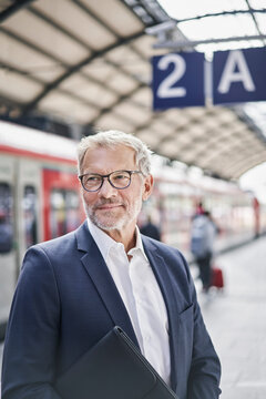 Male professional looking away while standing on railroad platform