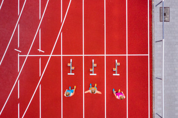 Germany, Baden Wurttemberg, Winterbach, Aerial view of three female sprinters standing at track starting block