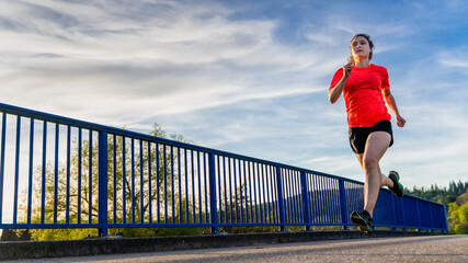 Young woman jogging along bridge