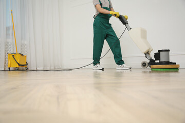 Professional janitor cleaning parquet floor with polishing machine indoors, closeup. Space for text