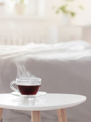 glass cup of coffee on white table in bedroom