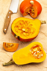 Sliced pumpkin and knife on brown paper.
