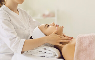 Obraz premium Beautician doctor make face lifting massage for woman client in aesthetic medicine clinic. Dermatologist or cosmetologist do beauty procedures in saloon or spa for female. Cosmetology concept.
