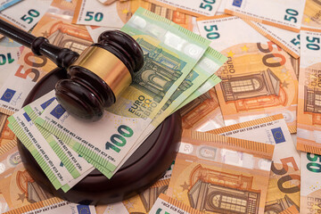 on the beautiful brand new euro bills lies a strong wooden gavel of the judge