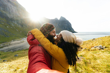 Hugging couple taking selfie near sea