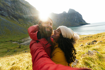 Traveling couple taking selfie against sea