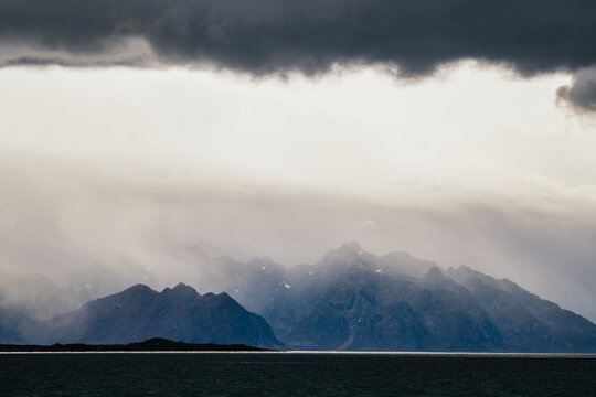 Mountains surrounding sea under cloudy sky