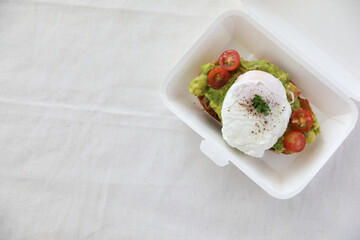Poached eggs with avocado on toast with delivery package in white background