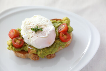Poached eggs with avocado on toast in white background