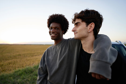 Male friends leaning on car in countryside