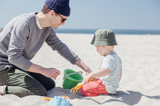 Father and son playing together with sand toys at beach