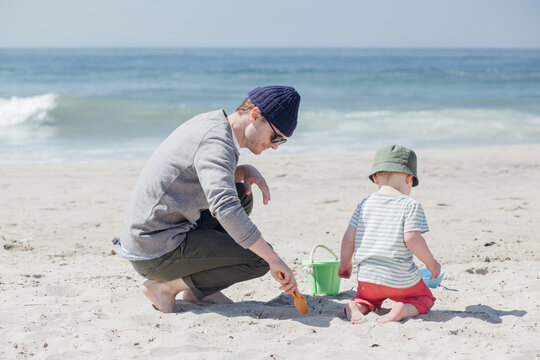 Father and son playing with sand toys at beach