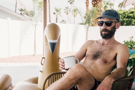 Shirtless man having coffee while relaxing at patio