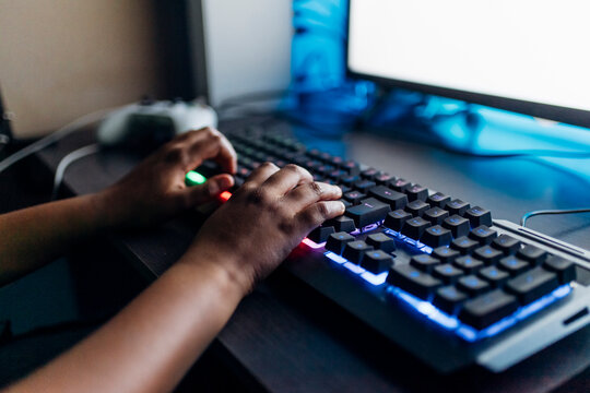 Boy playing game on computer through illuminated keyboard at home