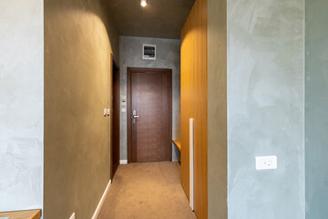 Interior of a carpeted hotel corridor doorway with brown wooden doors