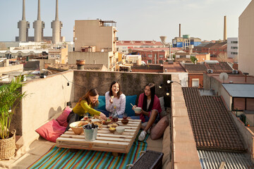 Female friends enjoying while eating on terrace