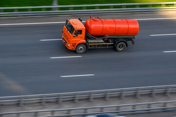 A large orange truck is driving along the road. Waste disposal services with a visit to the client....