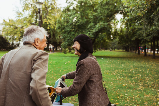 Happy elderly couple spending leisure time with electric bicycle in park