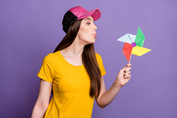Fototapeta na wymiar Photo of cheerful young happy woman blow air pinwheel toy good mood isolated on violet color background