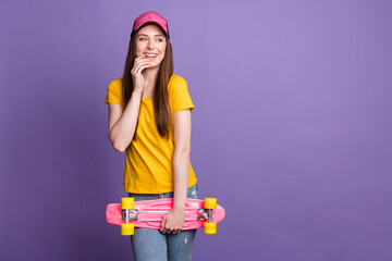 Photo of happy charming dreamy young woman look empty space hold skate isolated on violet color background