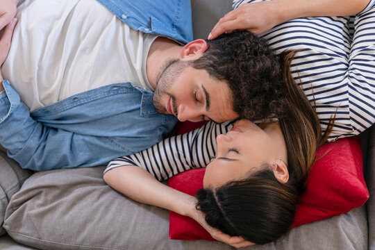 Boyfriend and girlfriend sleeping together on sofa at home